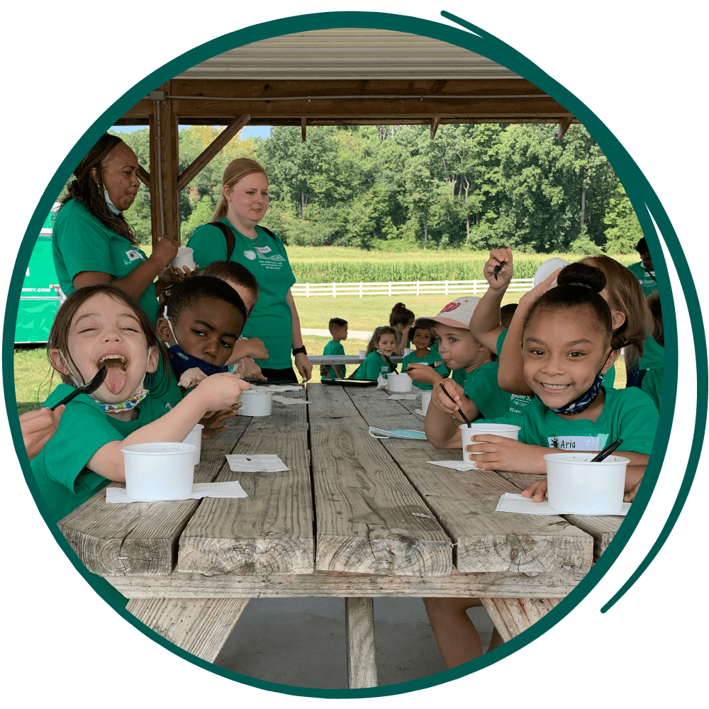 children eating ice cream at a picnic table.